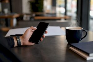 Hand holding phone near whiteboard in office